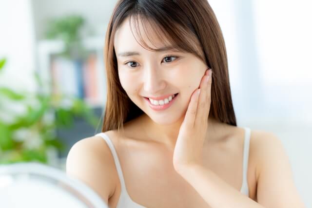 鏡を見てスキンケアする女性